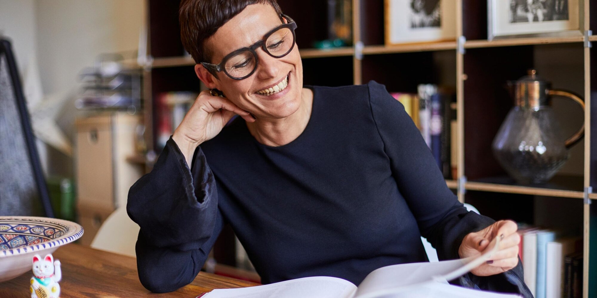 Frau mit Brille liest lachend ein Buch