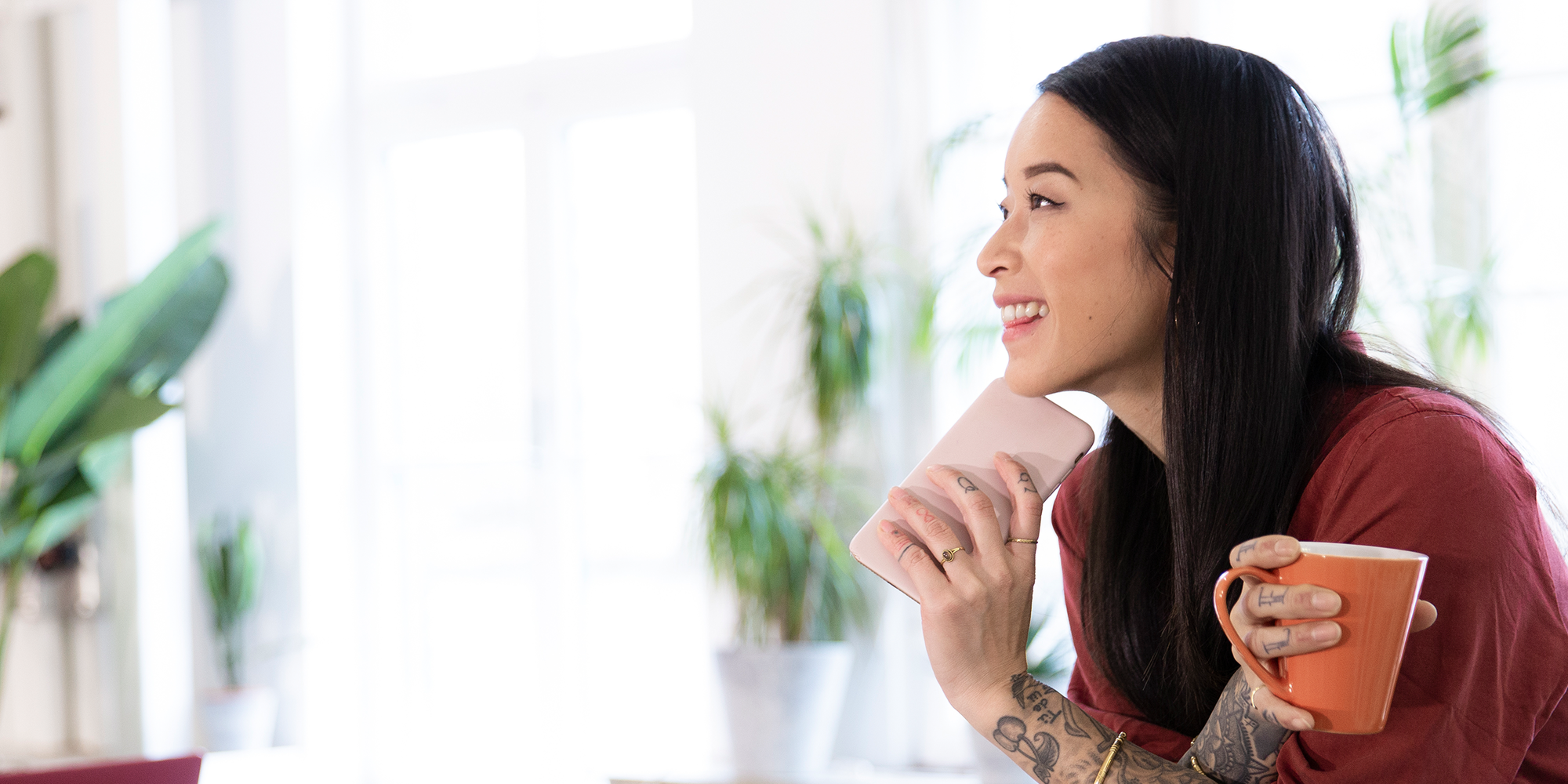Junge Frau mit Kaffee und Smartphone sitzt auf einem Sitzungstisch